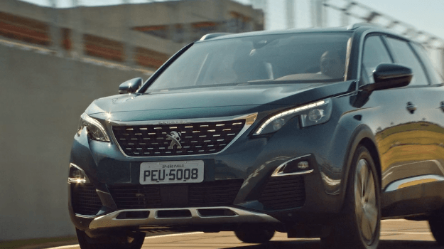 Um suv peugeot azul está estacionado na beira da estrada.