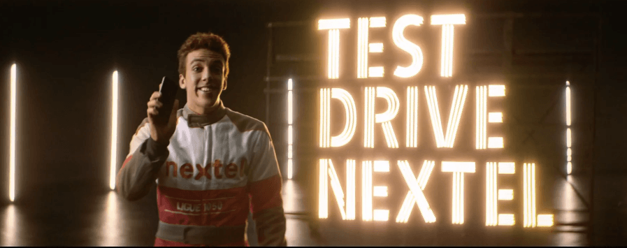 Um homem está parado em frente a uma placa que diz test drive nextel