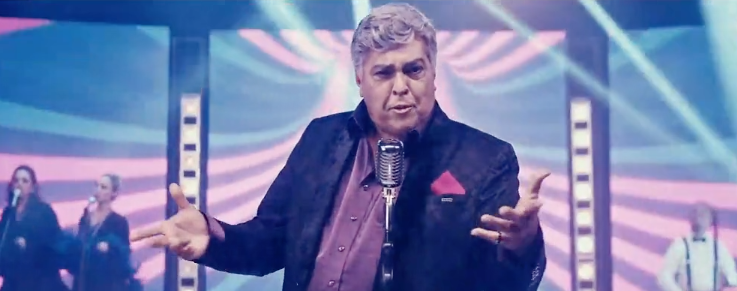 Um homem está diante de um microfone em um palco.