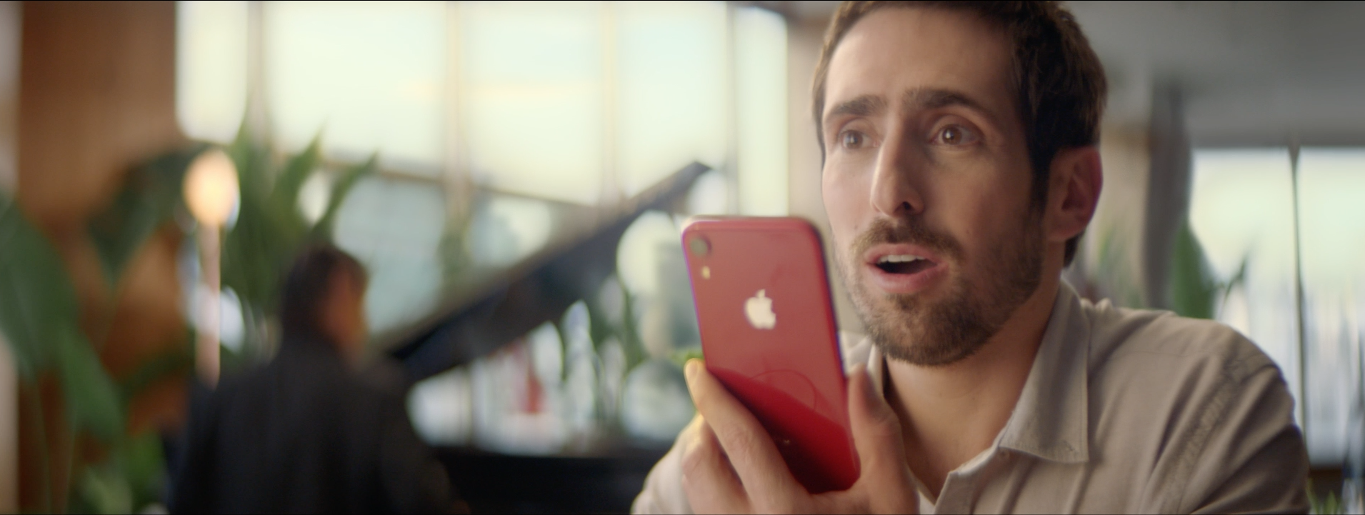 Um homem está segurando um iphone de maçã vermelha na mão.