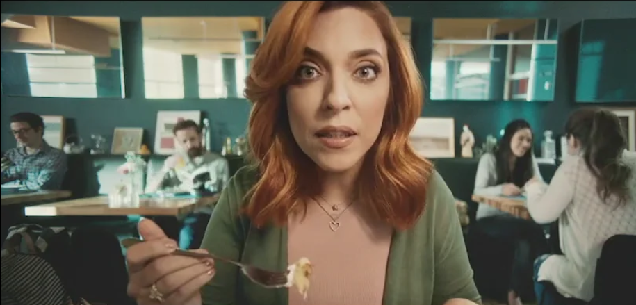 Uma mulher está comendo comida com um garfo em um restaurante.