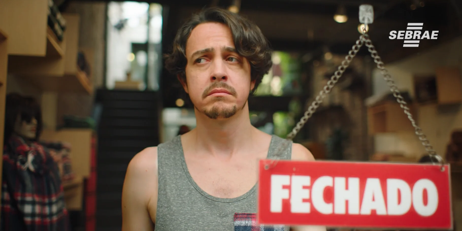 Um homem está segurando uma placa vermelha que diz fechado