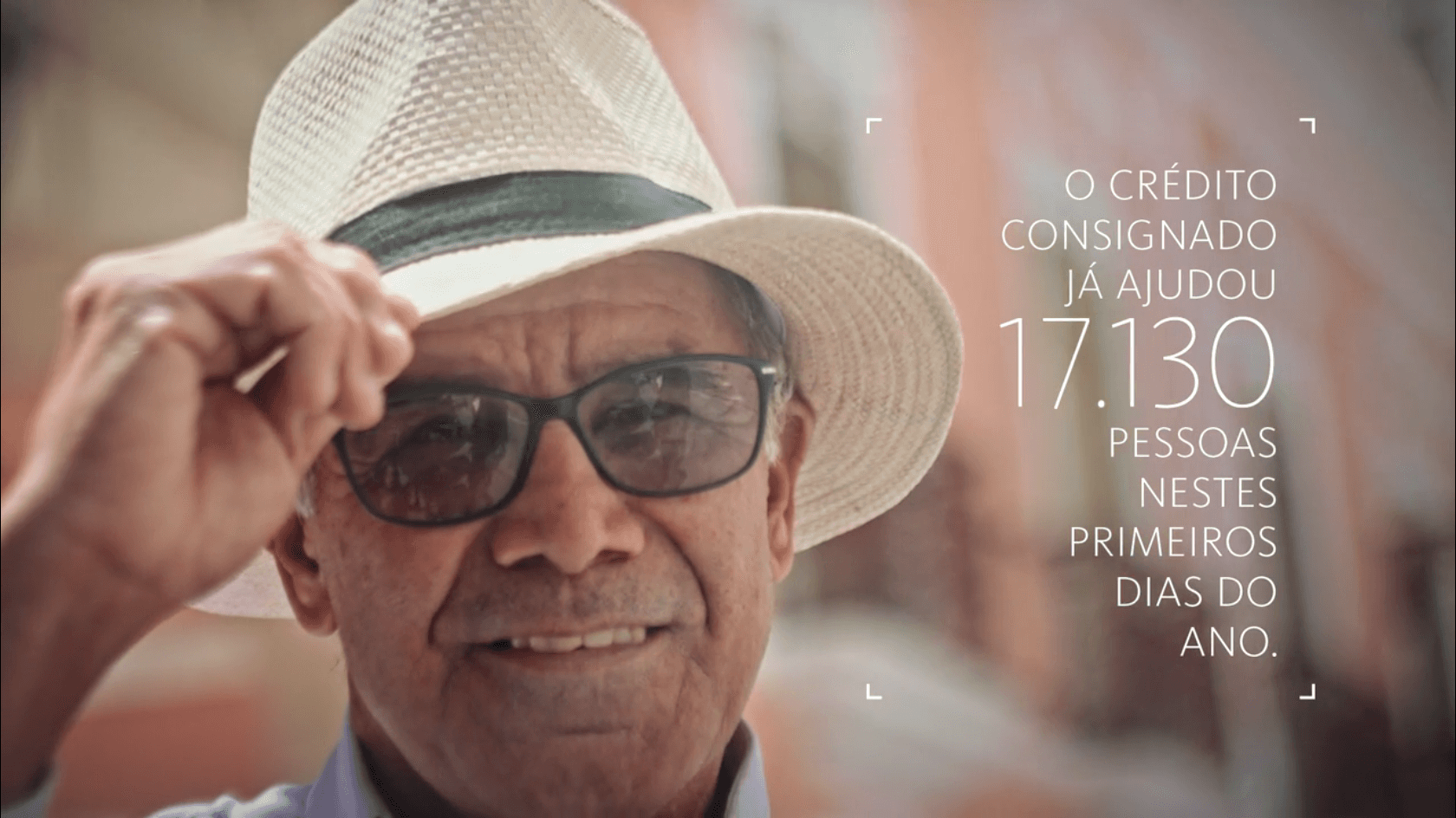 Um homem mais velho usando chapéu e óculos escuros está sorrindo.