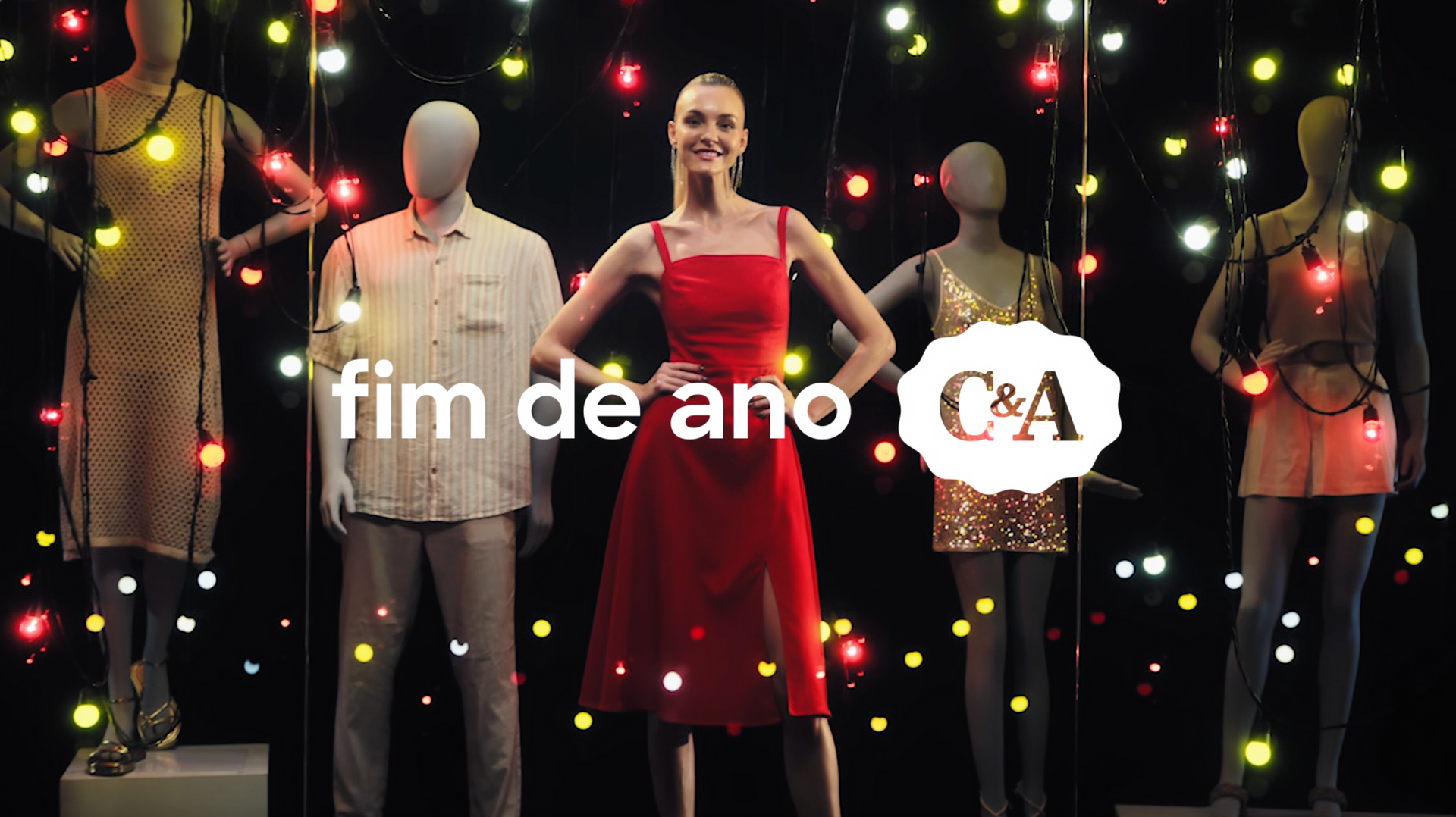 Uma mulher de vestido vermelho está diante de um grupo de manequins.