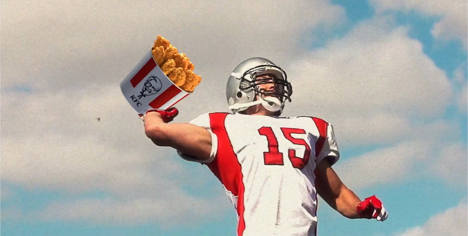 Um jogador de futebol com o número 15 na camisa está segurando um balde de batatas fritas