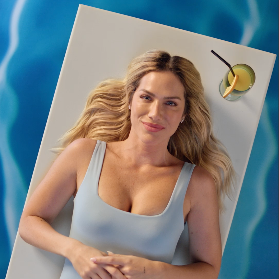 Uma mulher com uma blusa azul está deitada sobre um cobertor branco