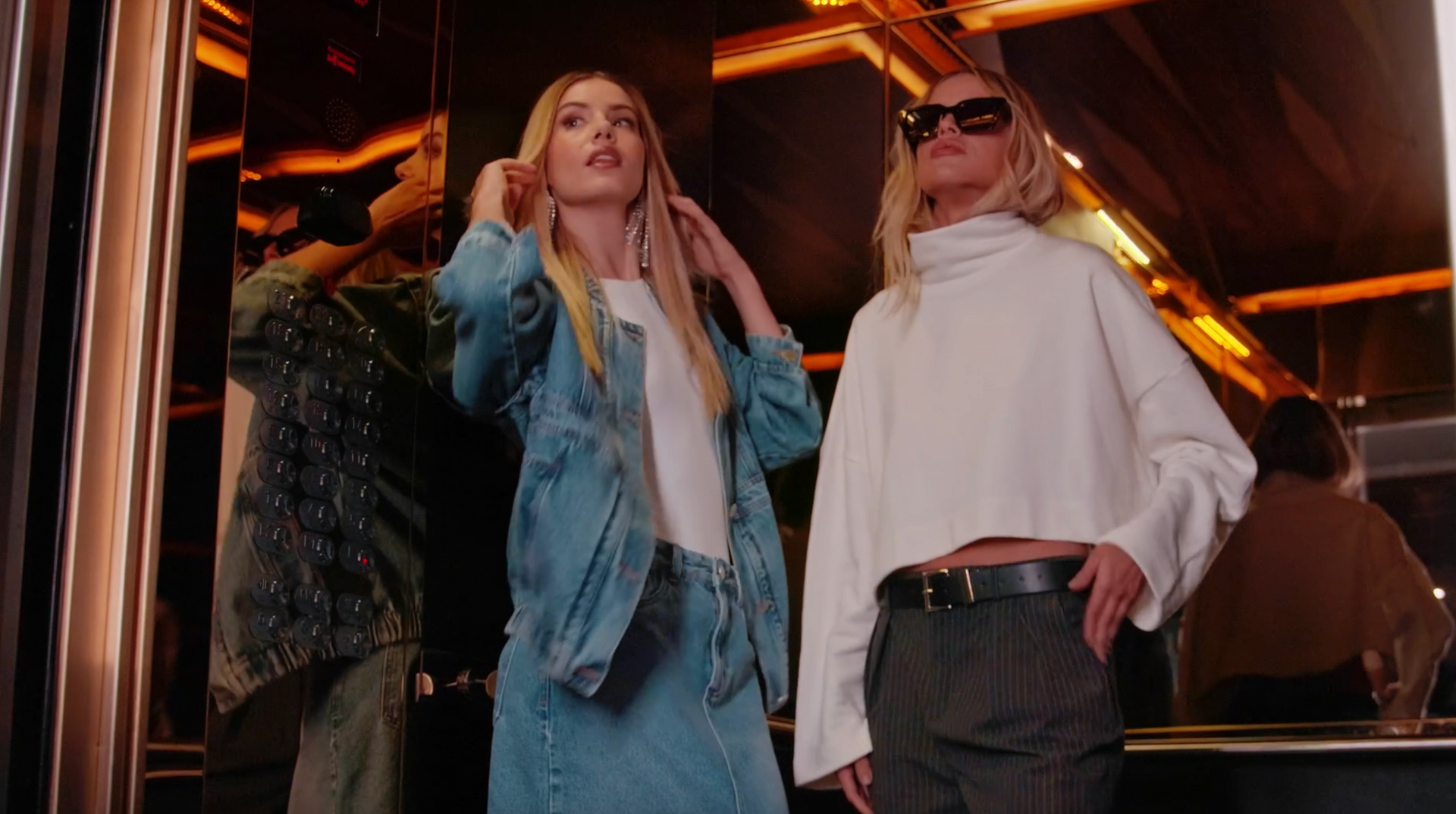 Duas mulheres estão lado a lado em frente a um espelho.