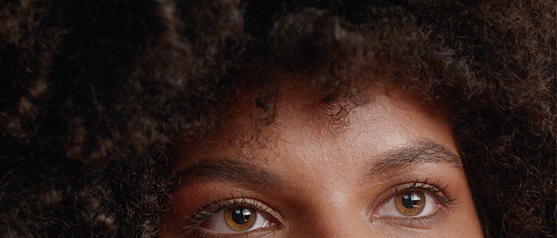 Um close dos olhos de uma mulher com cabelo afro.