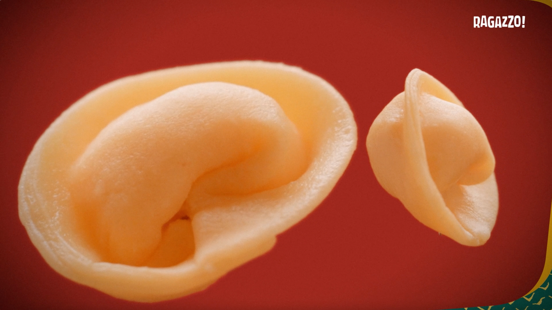 Um close de dois pedaços de macarrão em um fundo vermelho