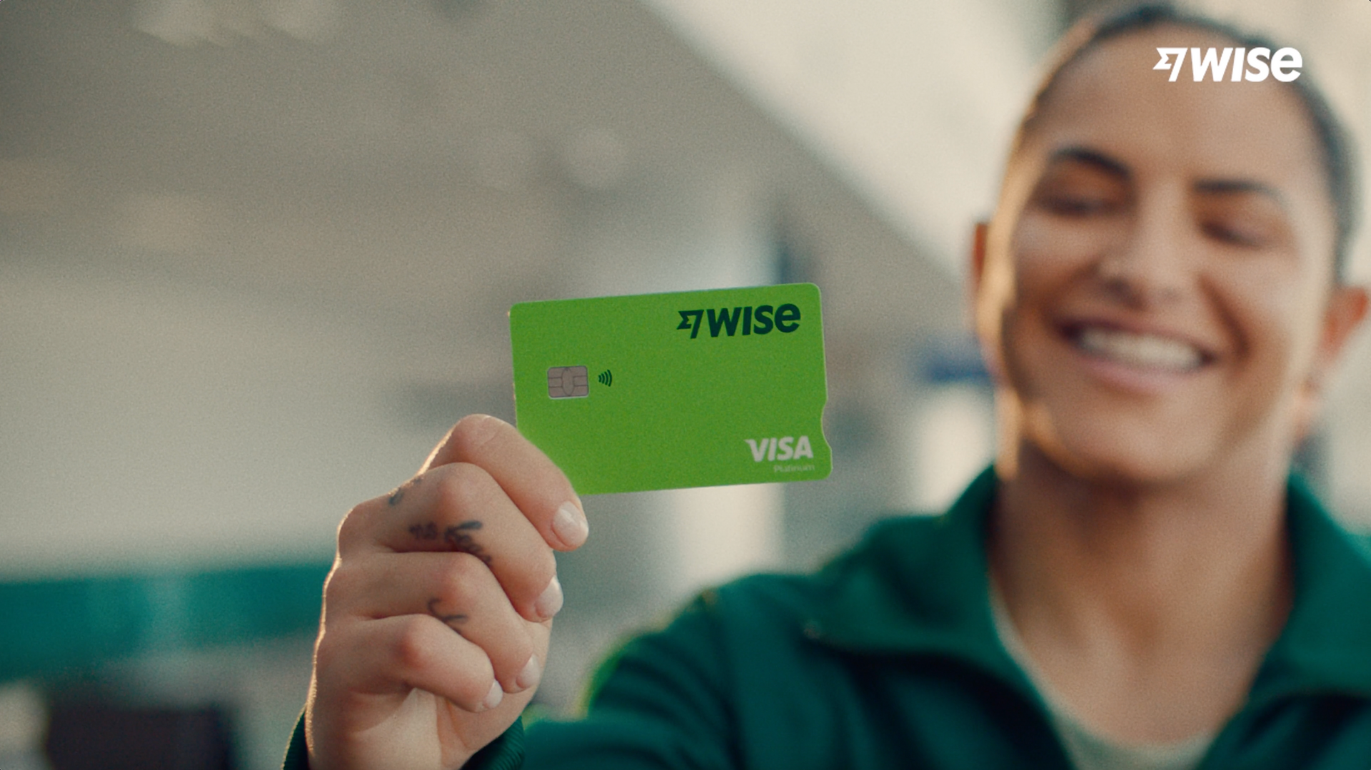 Uma mulher está segurando um cartão Visa verde na mão.