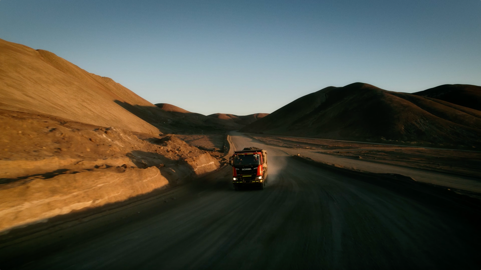 Um caminhão está dirigindo por uma estrada de terra no deserto.