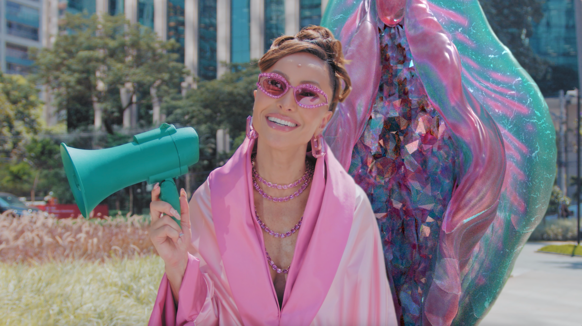 Uma mulher com uma túnica rosa está segurando um megafone verde.