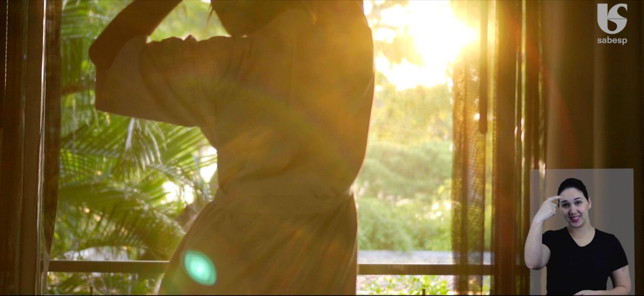 Um homem está parado em frente a uma janela com o sol brilhando através dela.
