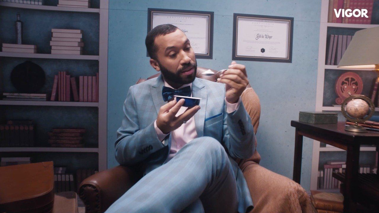 Um homem de terno e gravata borboleta está sentado em uma cadeira olhando para o telefone.