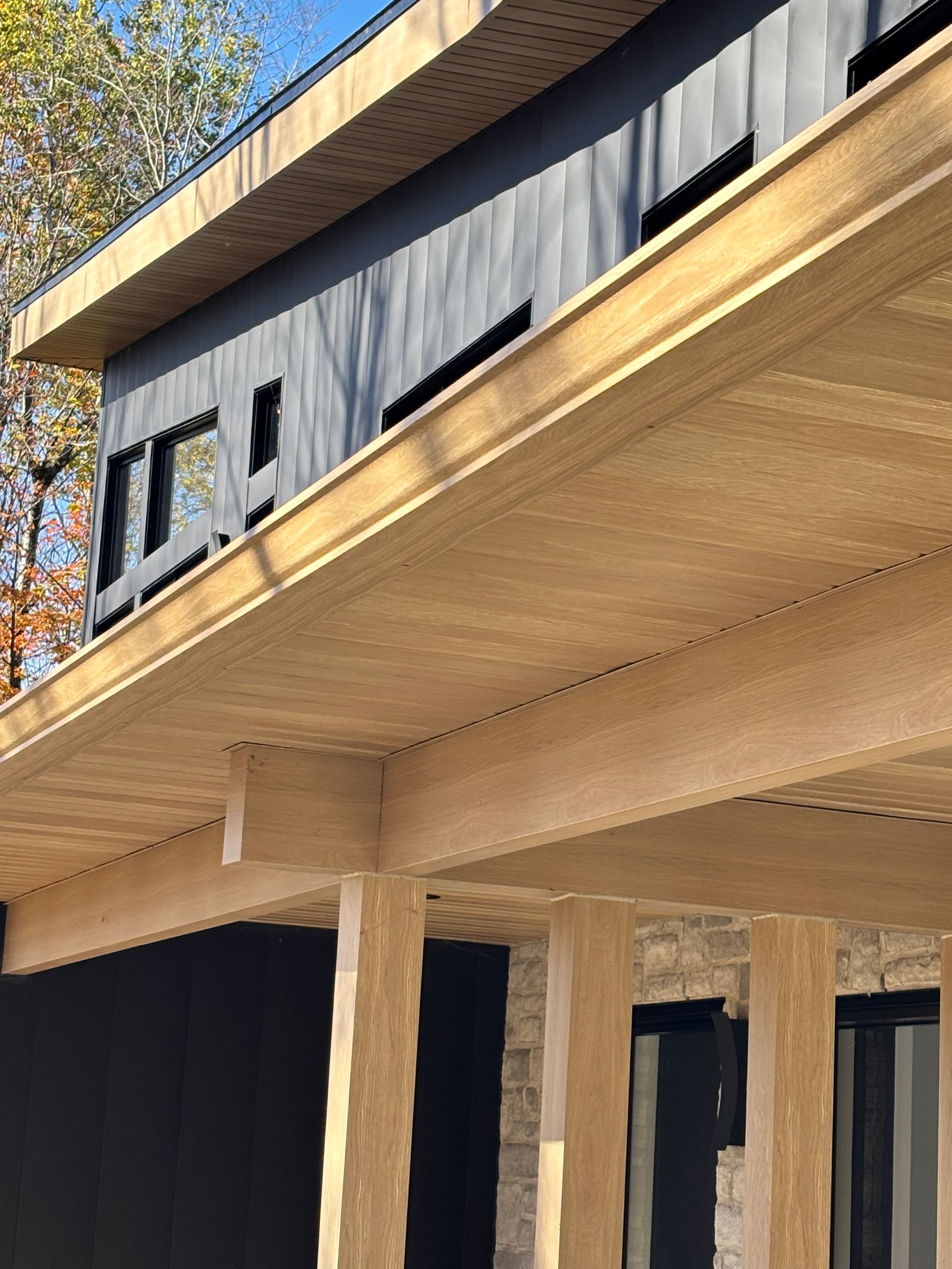 Un homme nettoie une gouttière avec des feuilles et des branches.