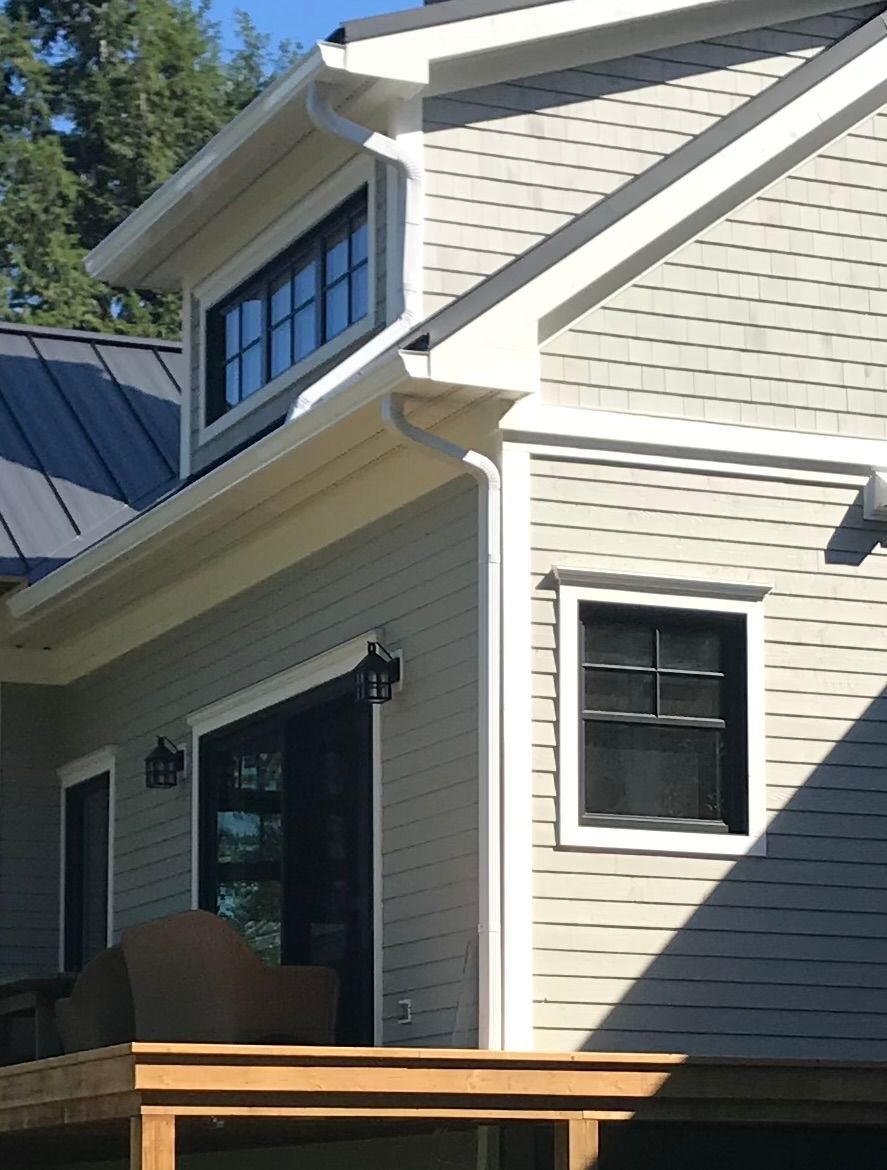 Une personne nettoie une gouttière de feuilles d'un toit.