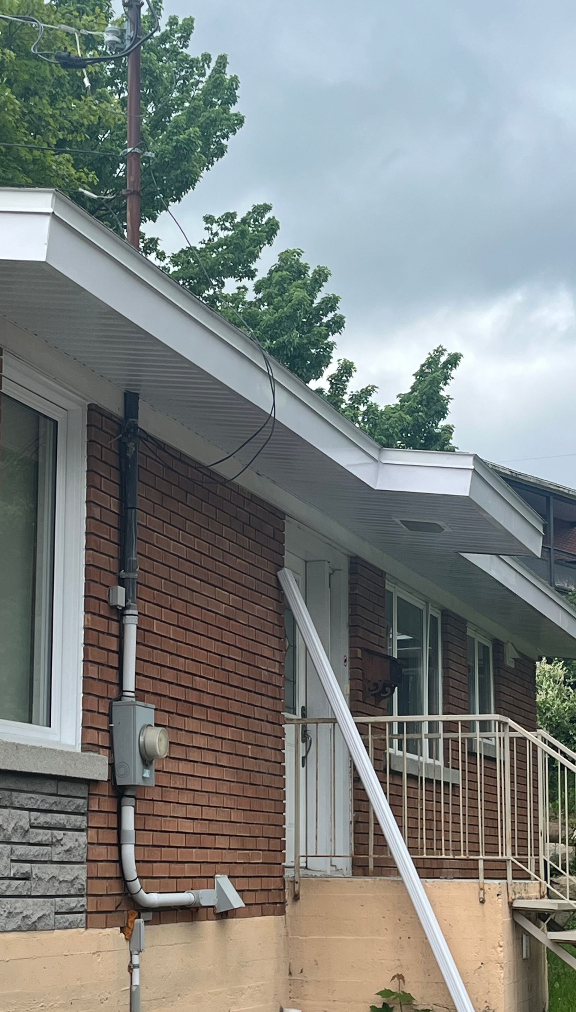 Vue aérienne d'un homme sur une échelle nettoyant les gouttières d'une maison.