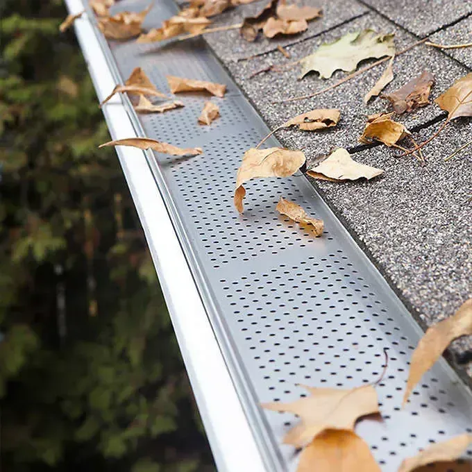 Un gros plan d'une gouttière avec des feuilles dessus.