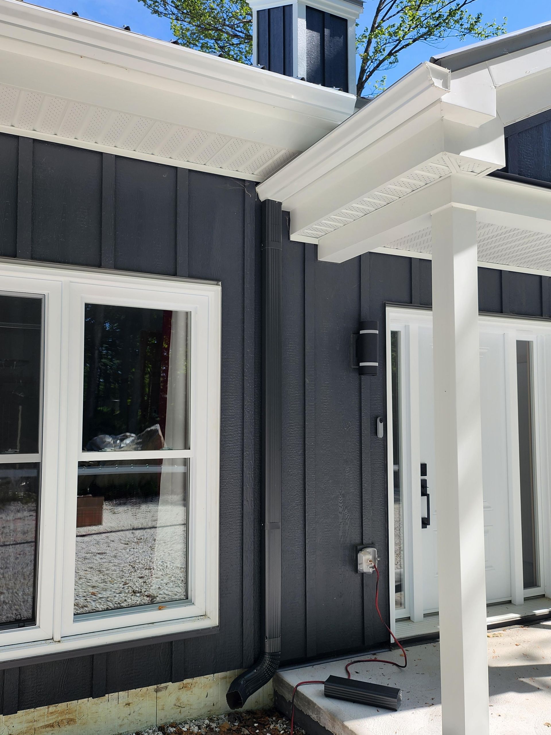 Une maison noire et blanche avec un porche et un toit.