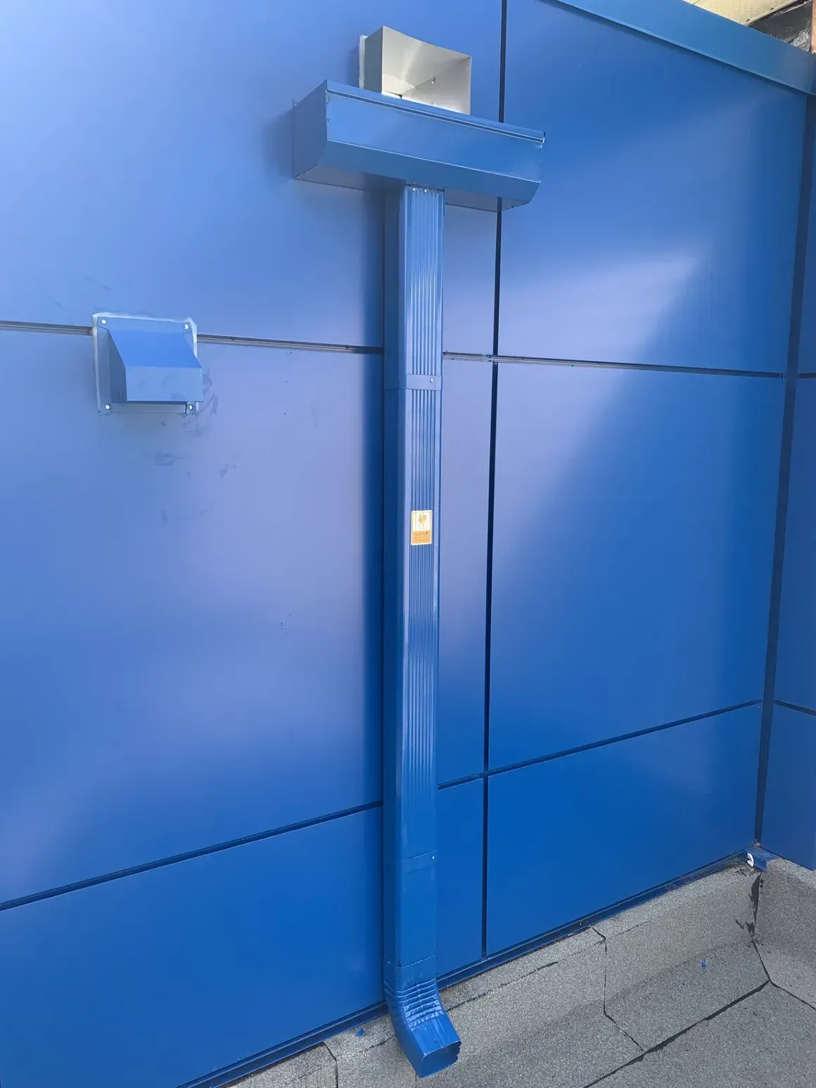 Un tuyau d'évacuation bleu est fixé à un mur bleu.