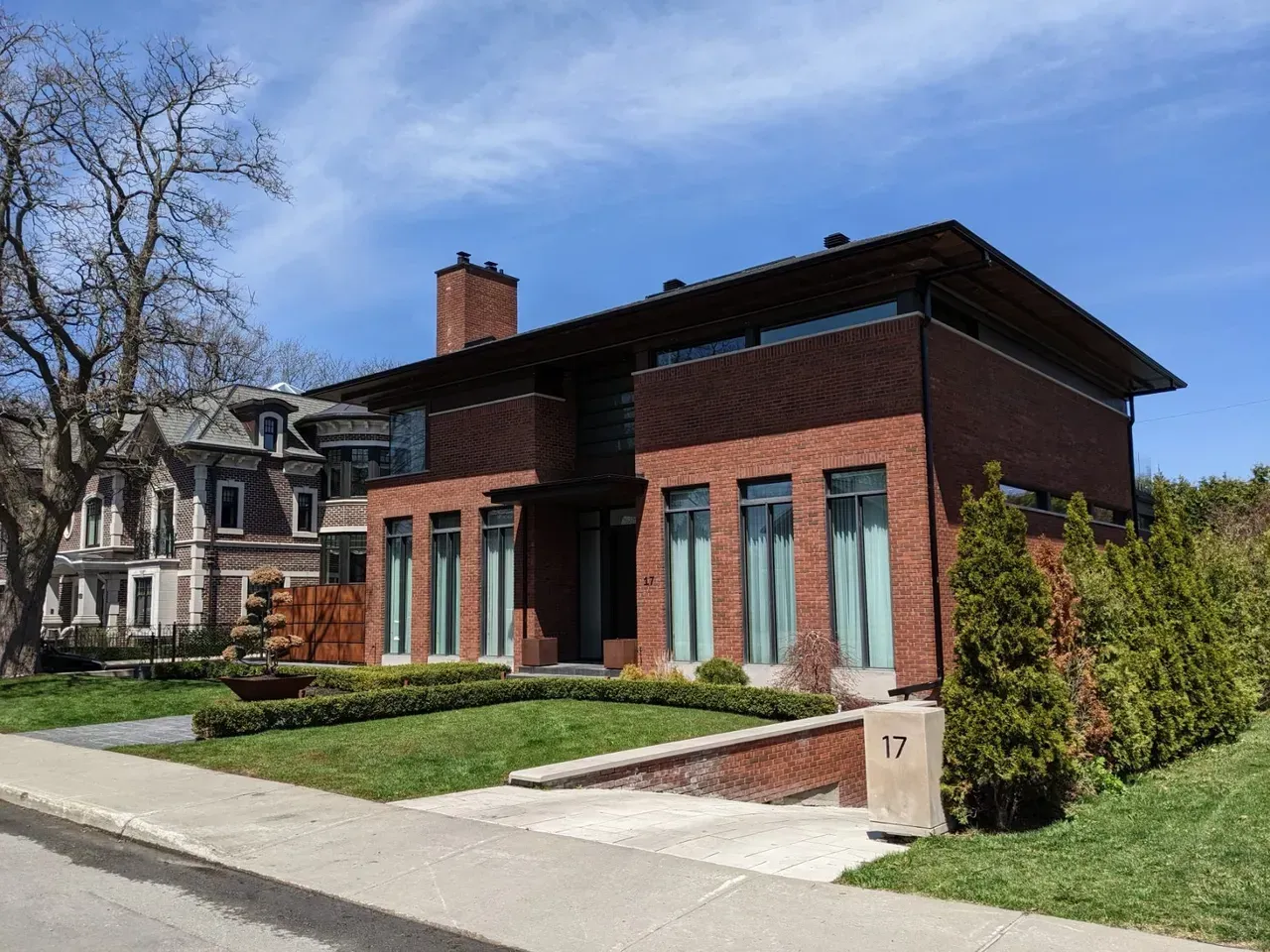 Une grande maison en briques avec beaucoup de fenêtres est située sur une pelouse verte luxuriante.