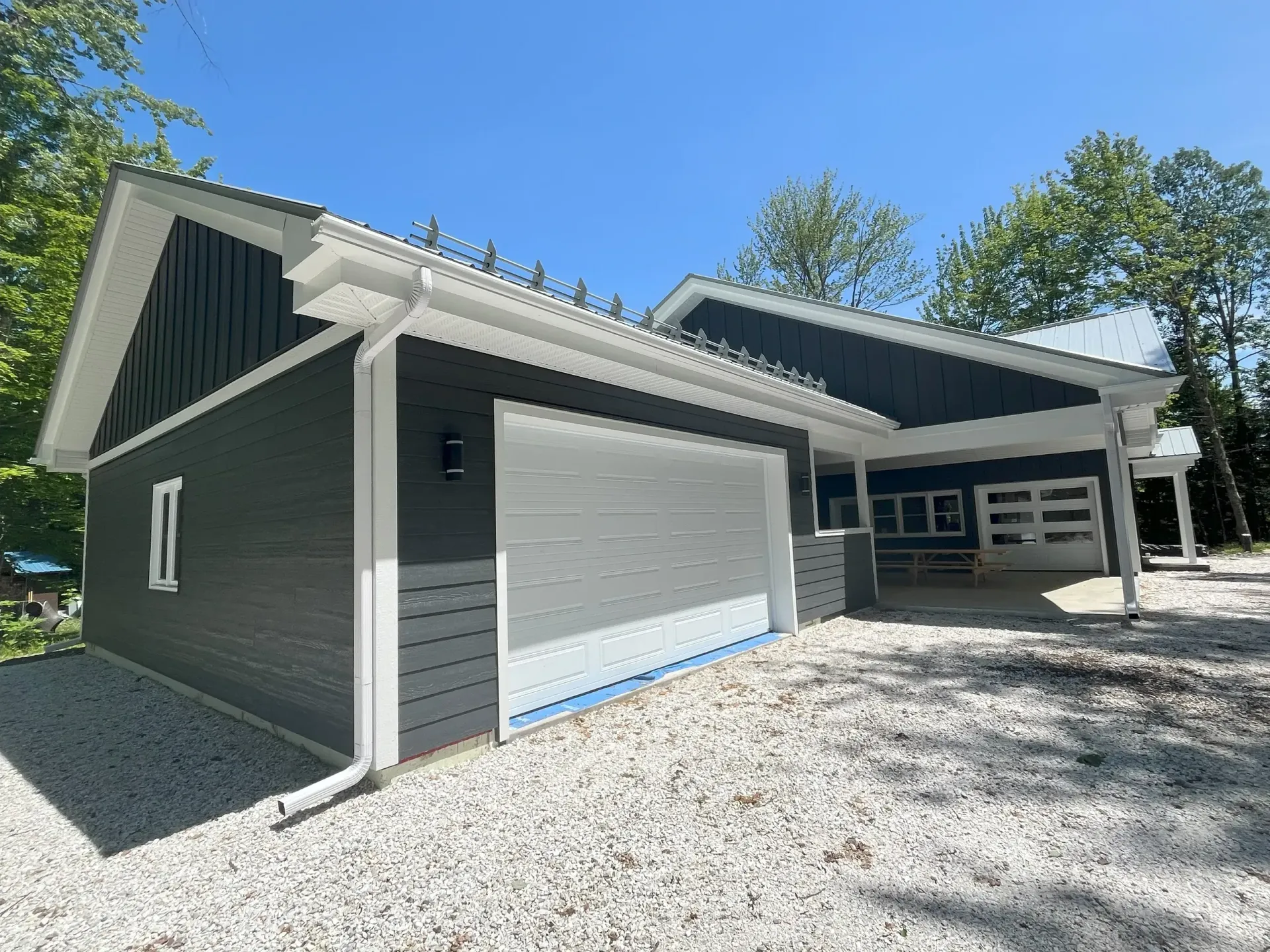 Une maison avec un garage et un abri voiture devant.