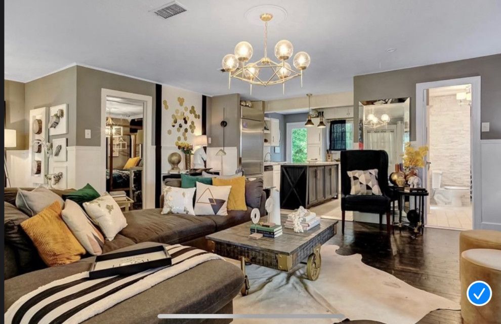 A modern living room with a gray sectional, gold chandelier, and a cowhide rug.