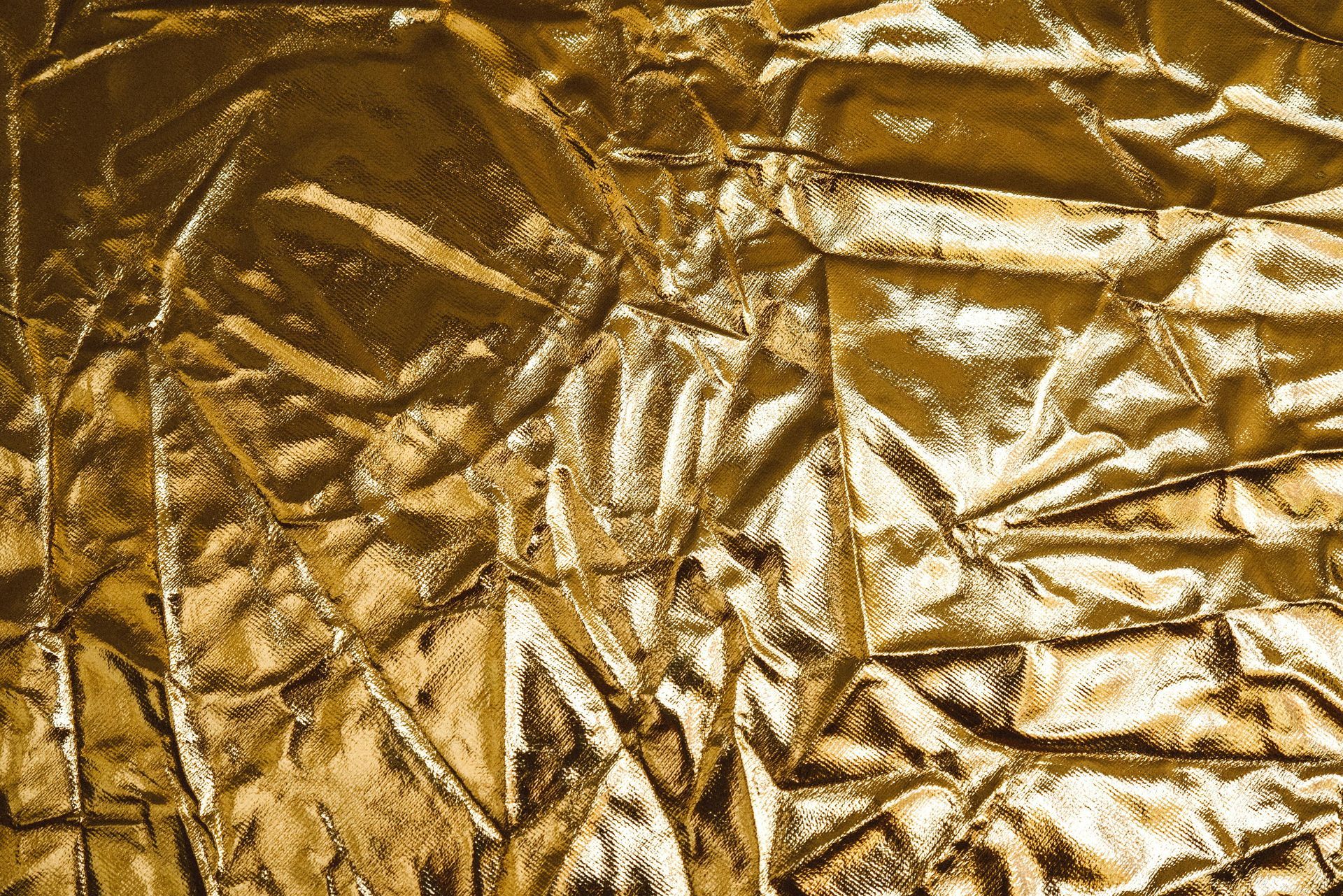 Crinkled gold foil, reflecting light with textured folds and highlights.
