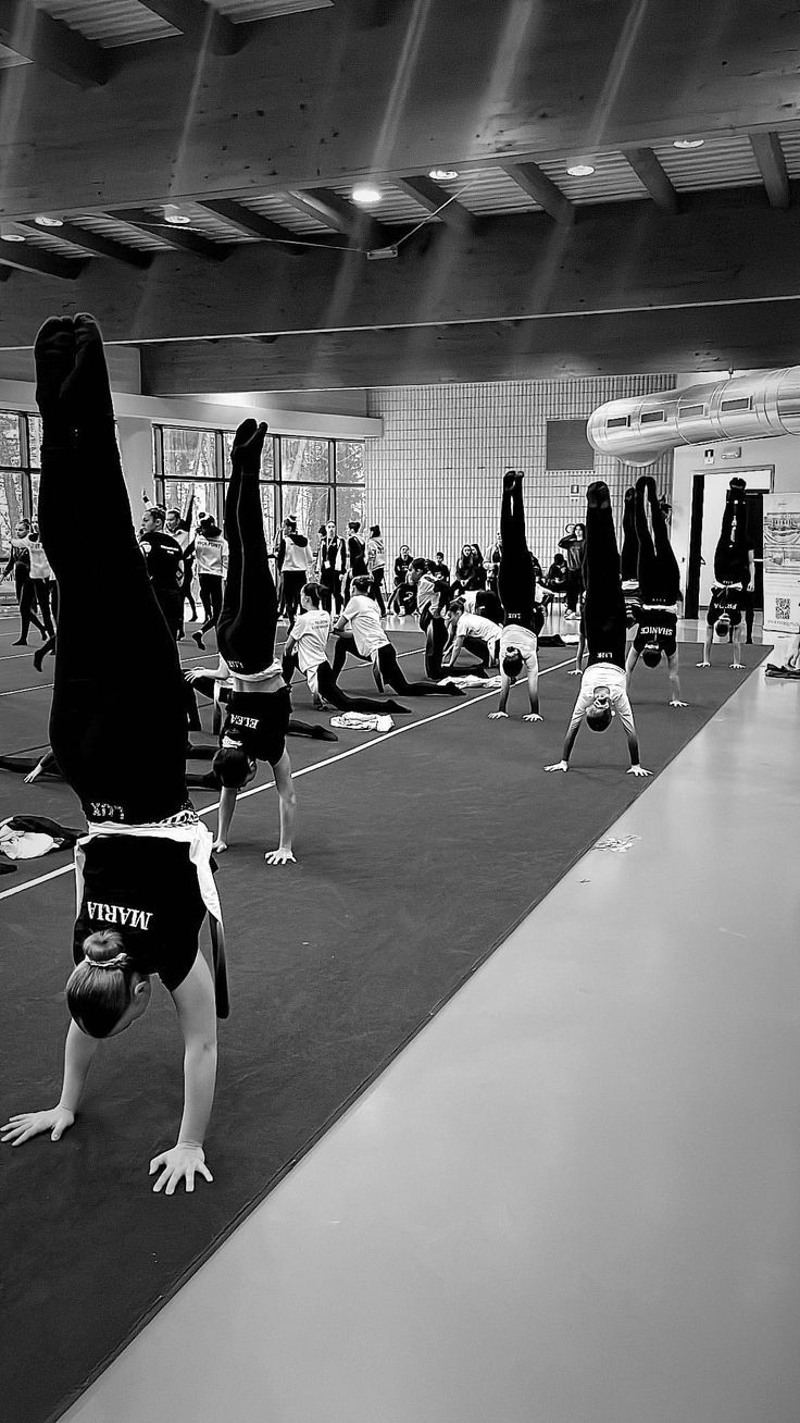 People doing handstands in a gym with others in the background.
