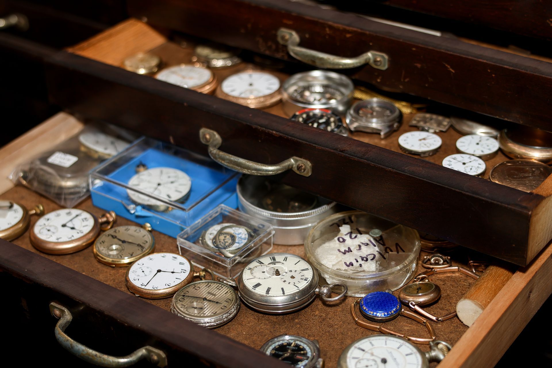 Drawers filled with antique pocket watches and watch parts.