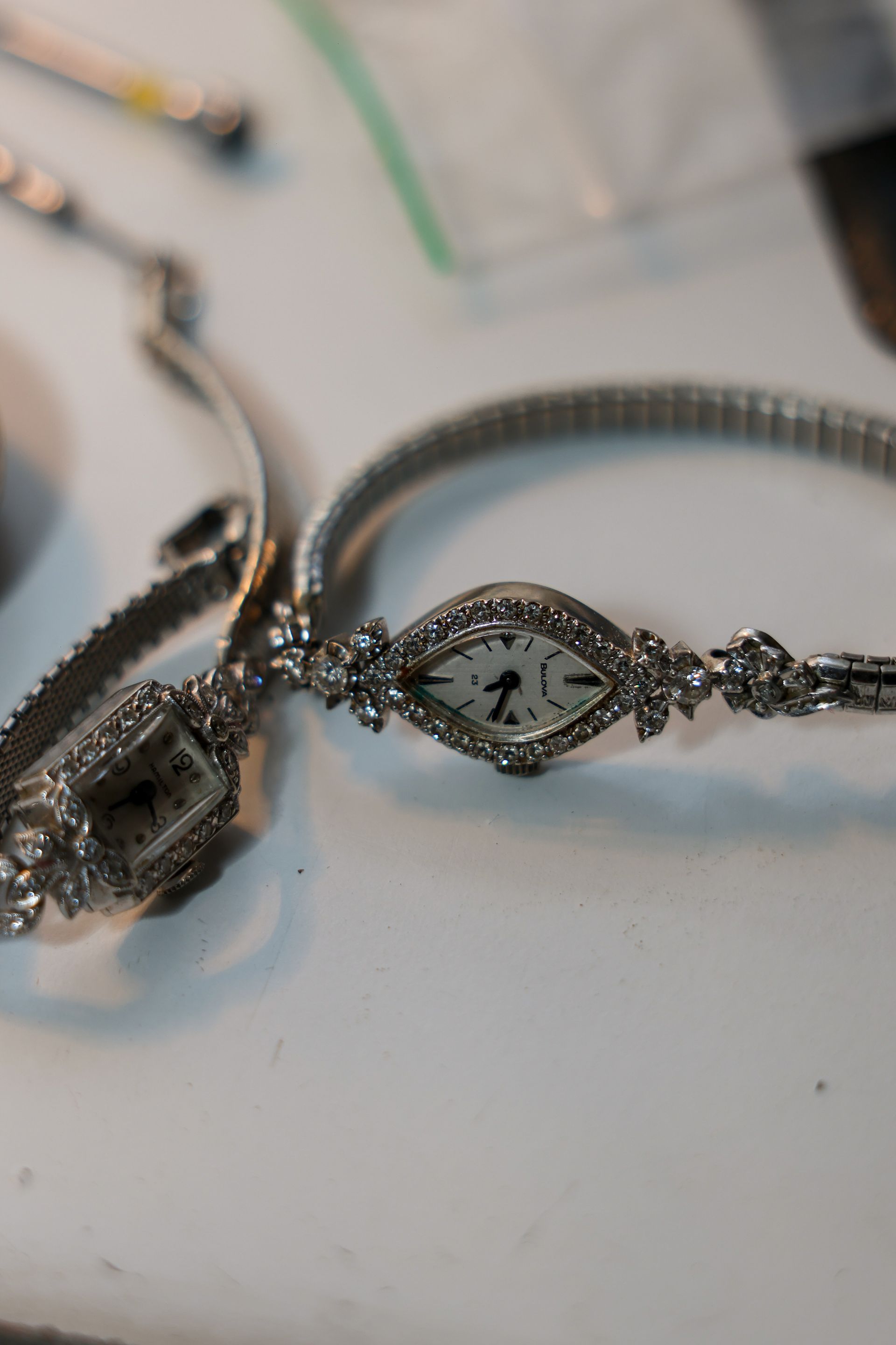 Two ornate silver wristwatches on a white surface, one with a diamond-shaped face.