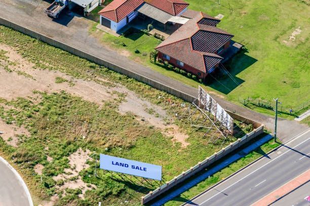 An aerial view of a land sale sign in front of a house.