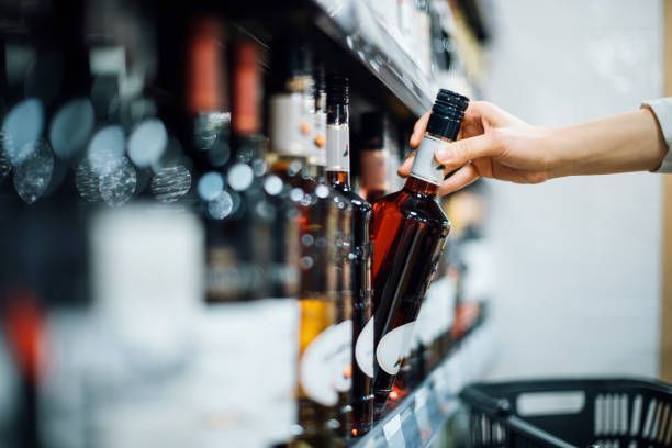 A person is taking a bottle of wine from a shelf in a store.