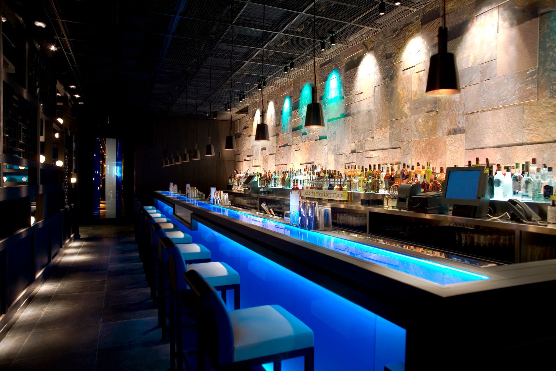 A long bar in a restaurant with blue lights on it