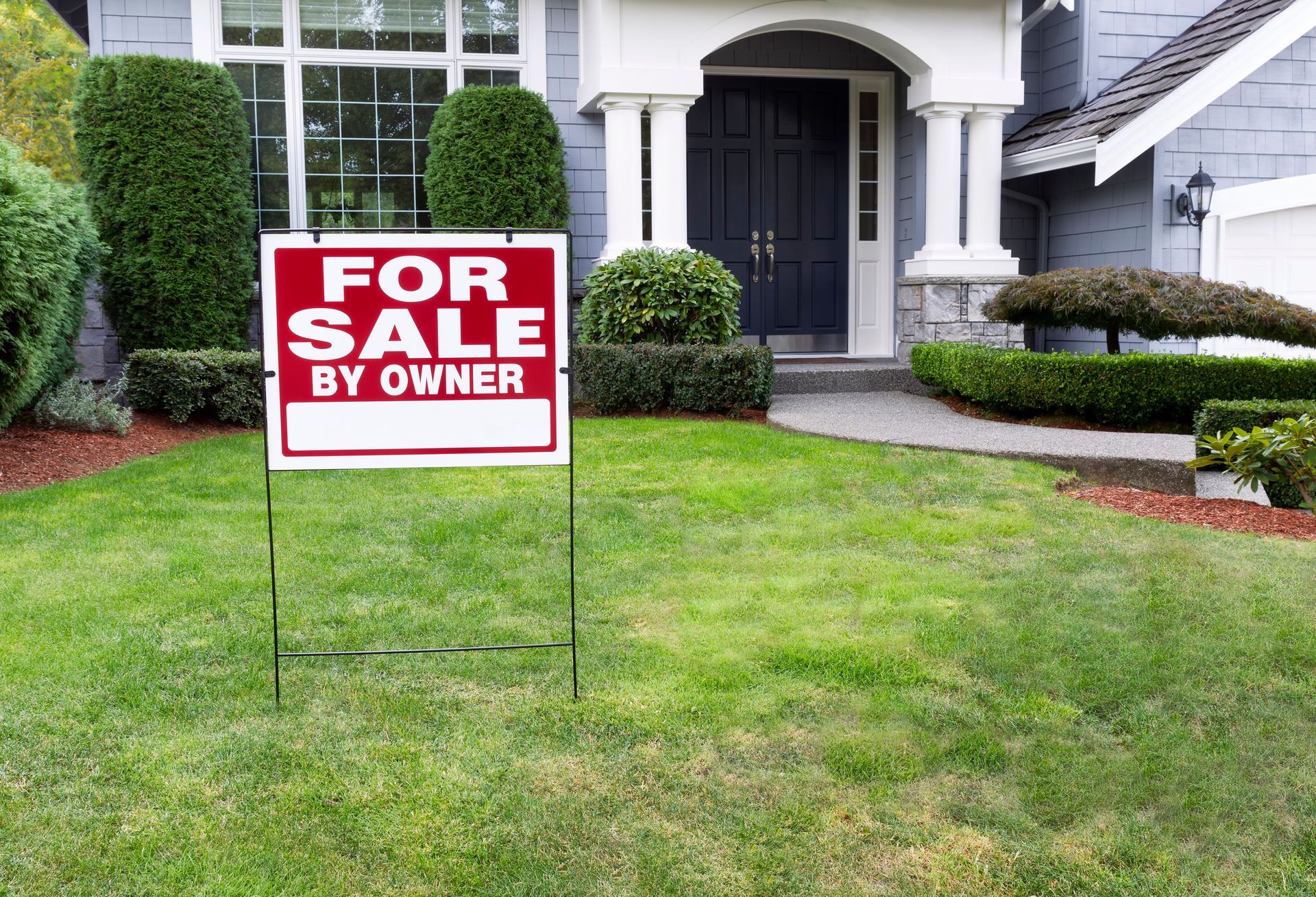 A for sale sign is sitting in front of a house.
