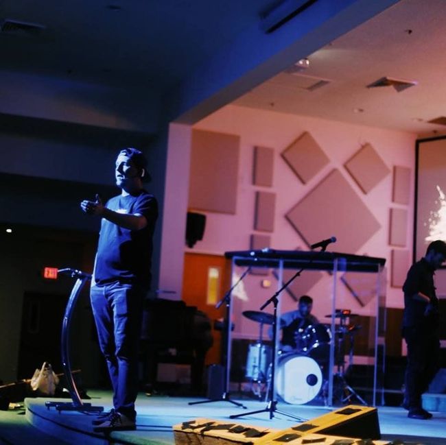 A man stands on a stage in front of a drum set