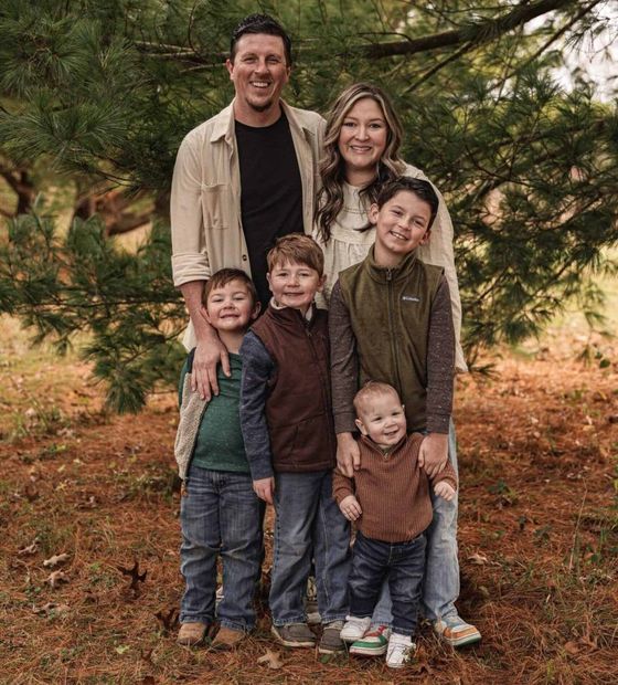 A family is posing for a picture in the woods.