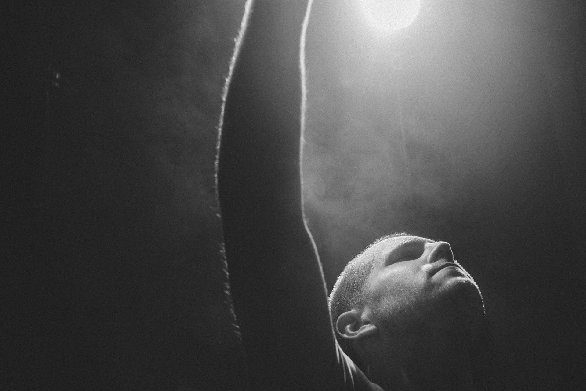 A black and white photo of a person looking up at the sky.