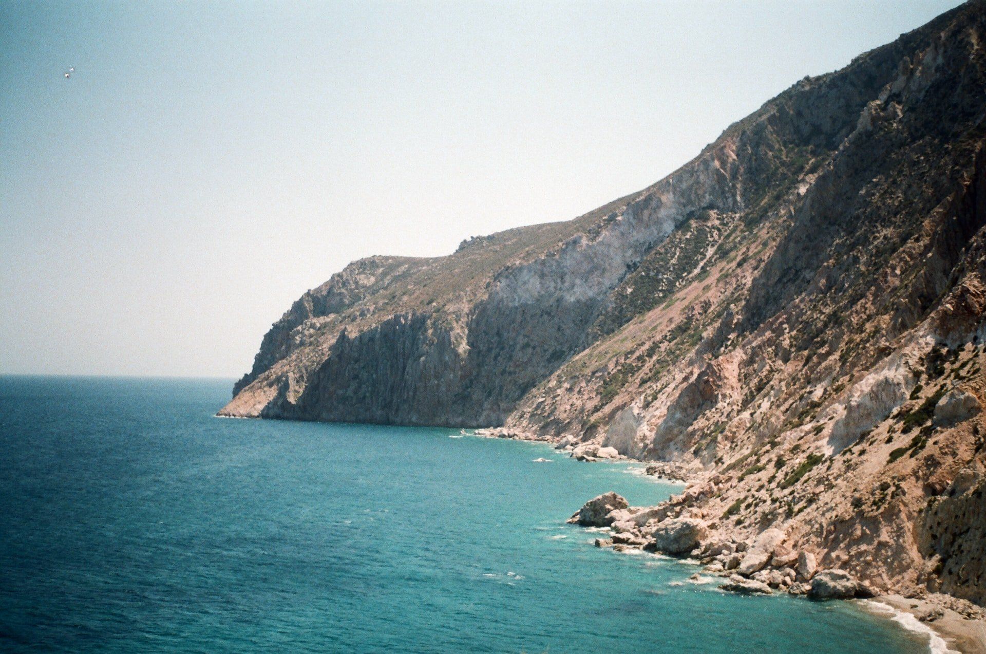 Rocky coastline meets turquoise sea under a clear sky.
