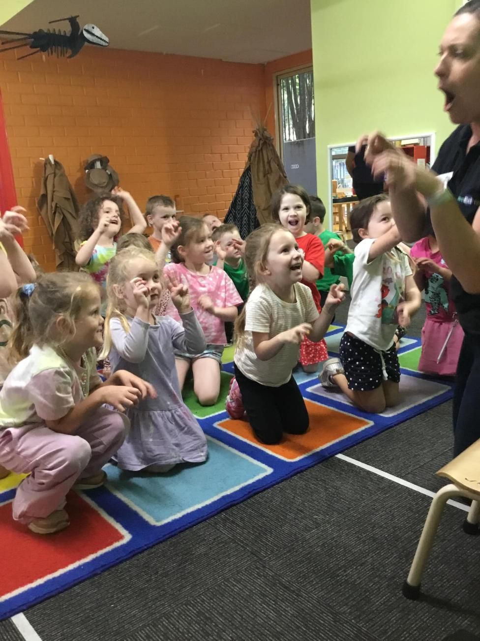 A Group Of Children Are Sitting On The Floor Watching A Man Perform A Trick — Moruya Drive Child Care Centre In Port Macquarie, NSW