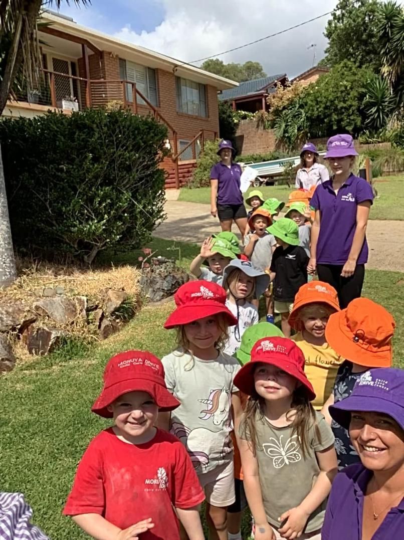 A Group Of Children Wearing Hats Are Standing In Front Of A House — Moruya Drive Child Care Centre In Port Macquarie, NSW