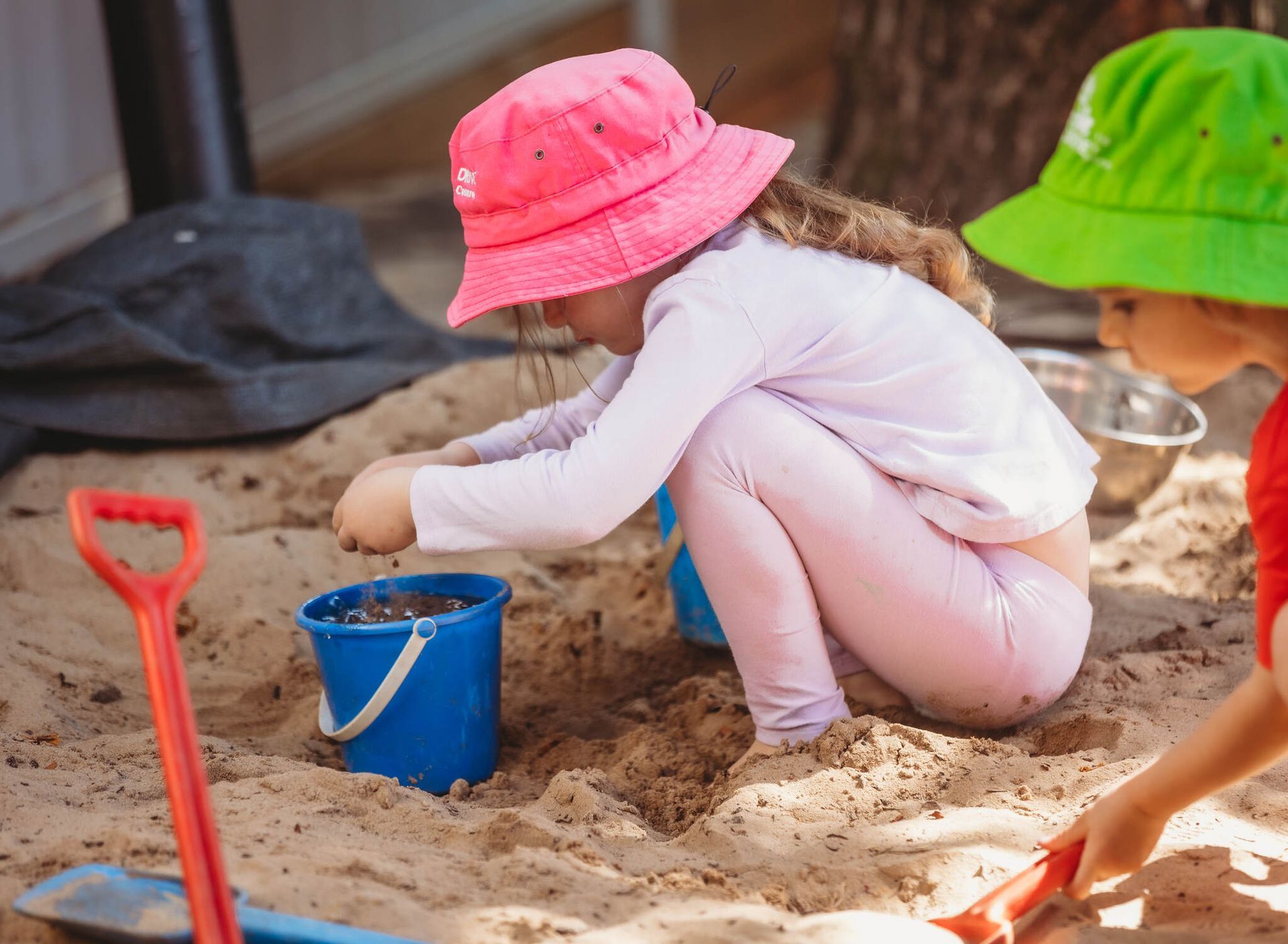 Two children are playing in the sand with buckets and shovels — Moruya Drive Child Care Centre In Port Macquarie, NSW