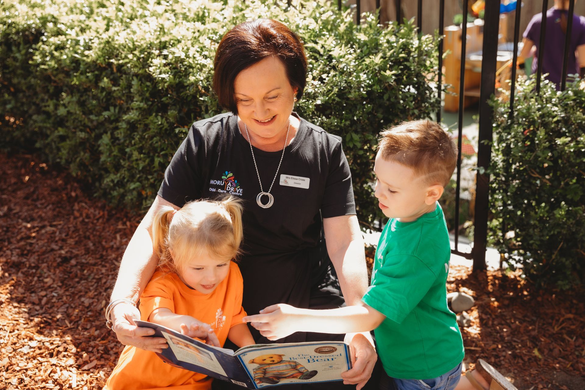 A woman is reading a book to two children.