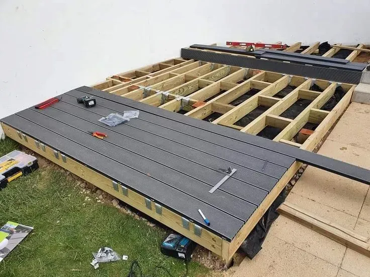 A wooden deck is being built in a backyard.