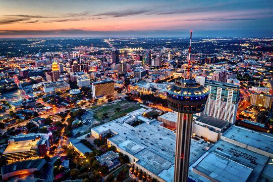 An aerial view of a city at night with a tower in the middle of the city.