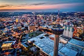 An aerial view of a city at night with a ferris wheel in the foreground.