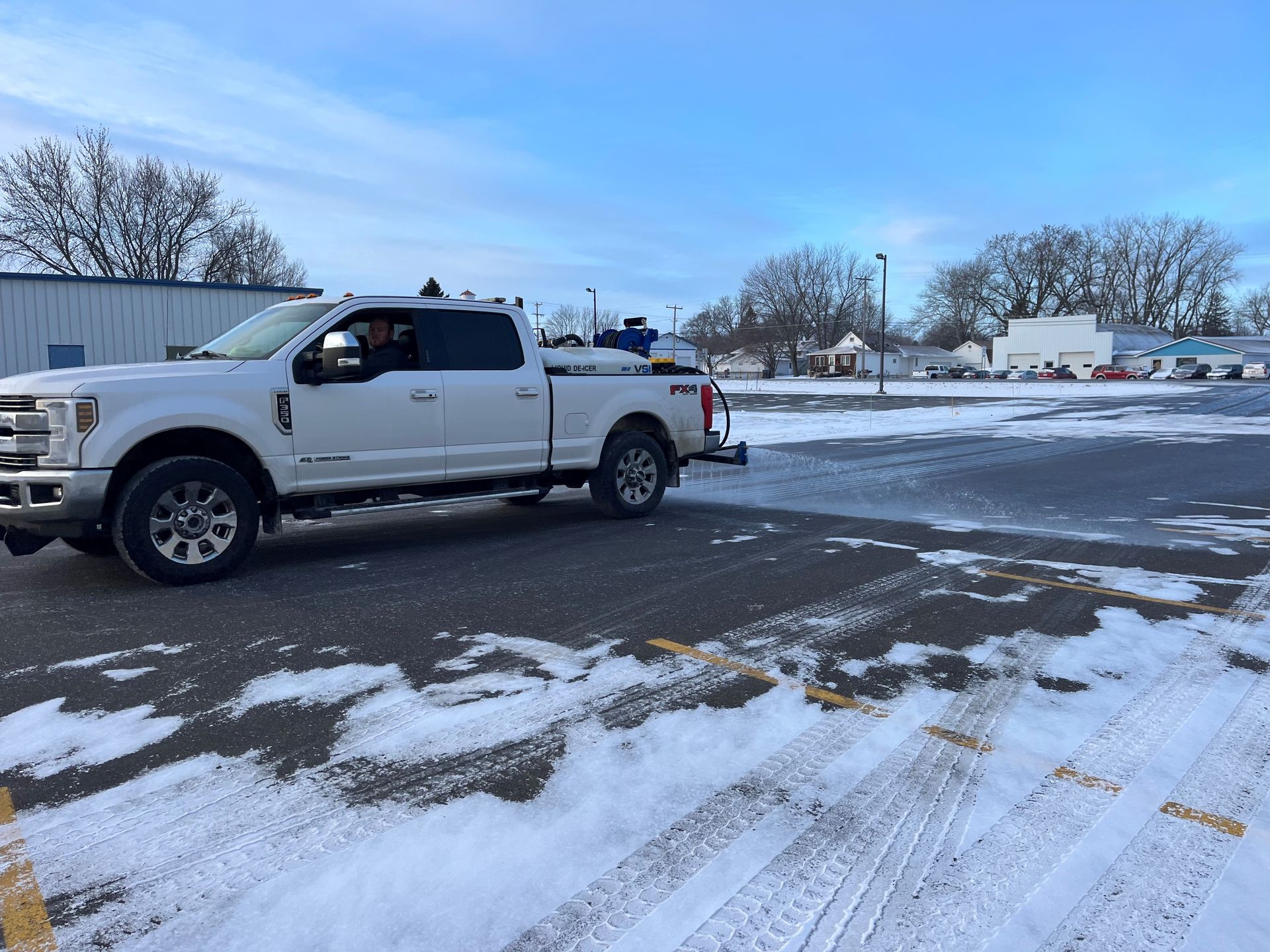 A white truck is parked in a snowy parking lot.