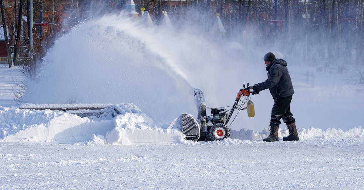 A man is using a snow blower to remove snow from the ground.