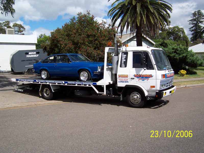 Flatbed Towing Truck With Blue Vintage Car — Trade & General Towing In Sandgate NSW