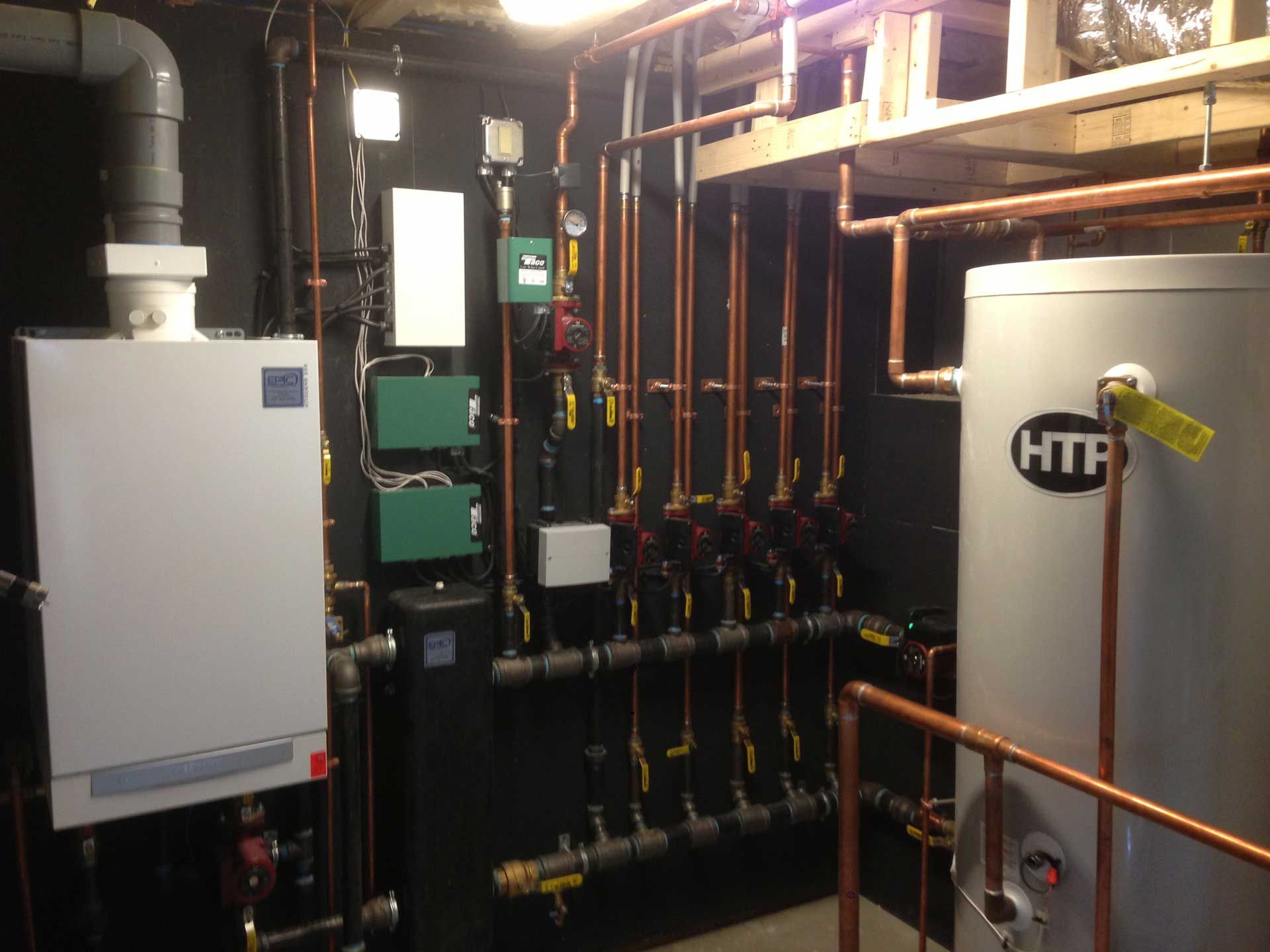 Furnace and water heater in a utility room with copper pipes and black walls.
